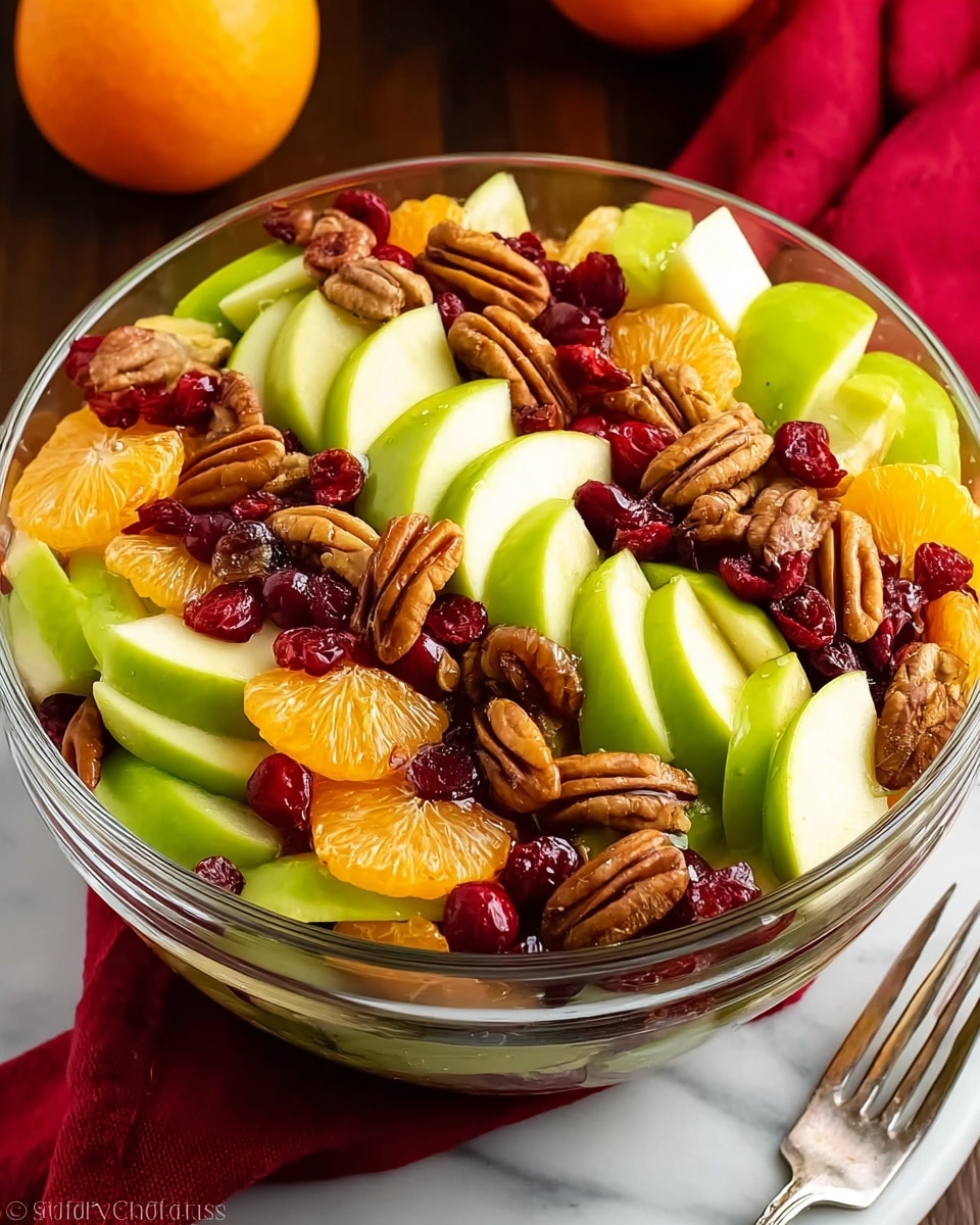 A clear glass bowl full of fresh fruit salad sits on a white marbled surface. The salad has three main layers: the bottom layer has bright green apple slices cut into wedges with smooth skins, the middle layer is made of shiny orange mandarin slices, and the top layer includes scattered whole pecans with a rich brown color and a crunchy texture, along with deep red dried cranberries, all mixed evenly. The fruits and nuts create a colorful and fresh look with a mix of smooth, juicy, and crunchy textures. A silver fork and a red cloth napkin are placed near the bowl. Photo taken with an iphone --ar 4:5 --v 7