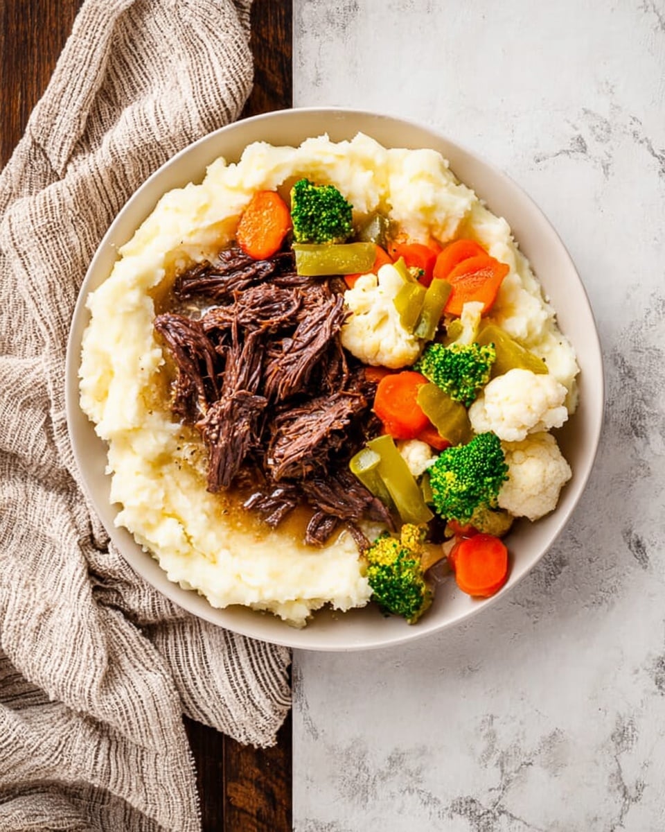 A white plate holds a single layer of creamy white mashed potatoes spread evenly across the bottom, topped with a layer of dark brown shredded beef pieces scattered on one side. On the other side, there is a colorful mix of steamed vegetables including bright orange carrot slices, green broccoli florets, and white cauliflower pieces. A few light green pepper pieces are placed over the beef. The plate sits on a white marbled surface, with a beige and white cloth casually draped near it. Photo taken with an iphone --ar 4:5 --v 7