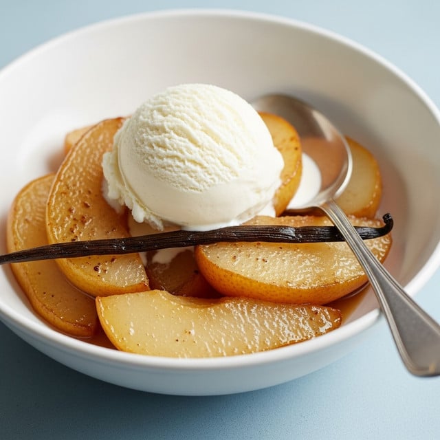 In a white scalloped bowl, there are several warm caramelized pear slices with a shiny, golden-brown surface, layered on the bottom and slightly overlapping. On top of the pears is a large scoop of smooth, creamy vanilla ice cream with a soft texture and tiny vanilla specks visible. A silver spoon rests inside the bowl, its handle leaning out. The bowl is placed on a white marbled texture, adding a clean background contrast. photo taken with an iphone --ar 4:5 --v 7