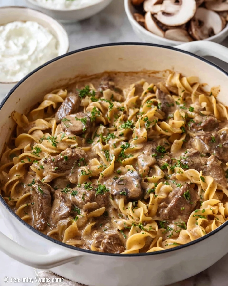 A close-up view of a creamy beef and mushroom noodle dish in a white pot. The dish has three main layers: the bottom layer is golden brown sauce that coats the thick, curly egg noodles which are light yellow with soft textures; the middle layer consists of browned beef pieces that look tender and juicy, scattered evenly throughout; the top layer has sliced mushrooms with a glossy texture and bits of green herbs sprinkled over, adding a touch of freshness. The pot is placed on a white marbled surface, and partially visible are a white bowl with sour cream and a plate with small diced white cheese cubes. photo taken with an iphone --ar 4:5 --v 7