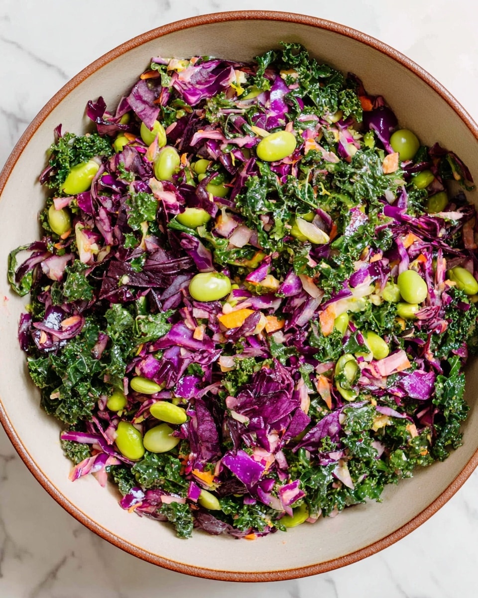 A large round bowl with a light beige inside and a brown rim is filled with a colorful mixed salad. The salad has many small chopped layers, including deep purple cabbage pieces, bright green kale leaves, and light green broad beans scattered evenly throughout. Some small bits of orange and pale green vegetables add more color variety. The ingredients have a fresh, slightly glossy texture, looking well mixed but not crushed. This bowl is sitting on a white marbled surface. photo taken with an iphone --ar 4:5 --v 7