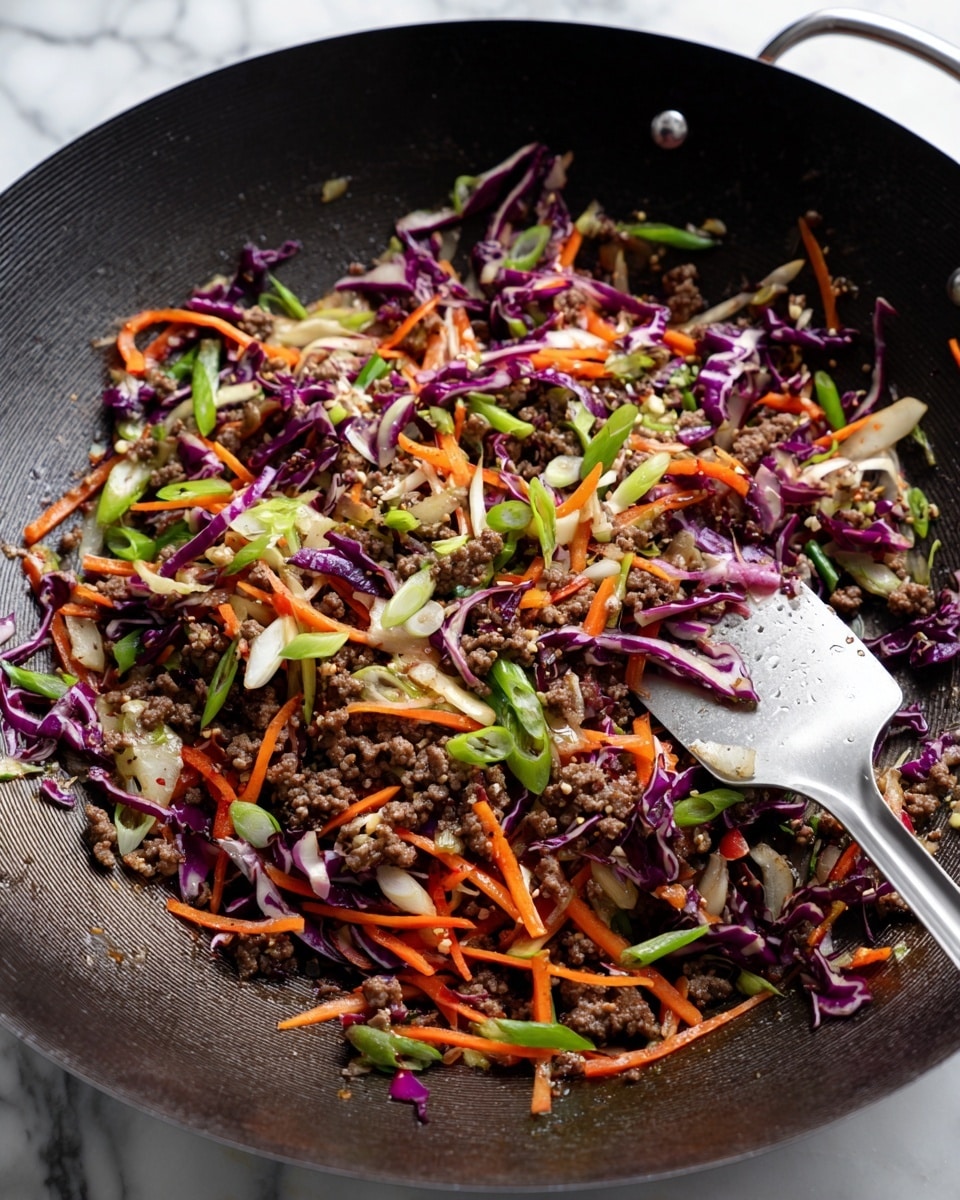 A large black wok filled with a colorful stir-fry mixture, showing roughly three main layers: a base of small browned ground meat and bits of cooked onions with a crumbly texture, mixed with thinly shredded bright orange carrot sticks and purple cabbage strips, scattered with light green sliced scallions on top. The vegetables look slightly softened but still fresh and crisp. A silver metal spatula rests inside the wok stirring some of the ingredients. The background surface is a white marbled texture. Photo taken with an iphone --ar 4:5 --v 7