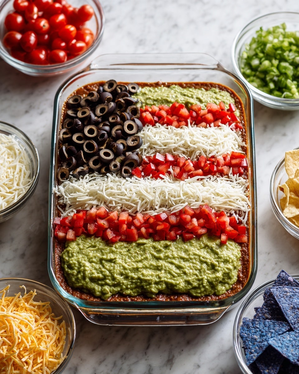 A clear rectangular glass dish shows a layered dip designed like the American flag. The bottom visible layer is light brown, topped with a smooth green layer. Over this are alternating stripes of white shredded cheese and bright red chopped tomatoes, creating five stripes. In the top left corner, there is a square made of a white cheese base covered with a thick layer of sliced black olives. The dish is set on a white marbled surface, surrounded by small clear bowls filled with shredded cheese, diced tomatoes, and guacamole topped with small tomato pieces, with a wooden bowl of blue corn chips nearby. Photo taken with an iphone --ar 4:5 --v 7
