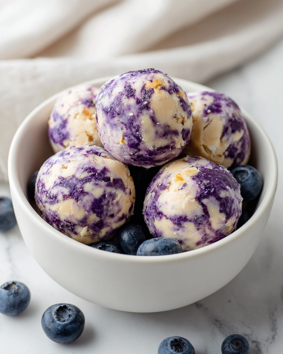 A white bowl holds five round pieces of food, each with a marbled mix of purple and cream colors, showing a soft, textured surface. The purple parts look smooth and slightly shiny, while the cream parts have a more matte, rough look. Fresh blueberries are scattered around the round pieces inside the bowl. The bowl sits on a white marbled surface. photo taken with an iphone --ar 4:5 --v 7